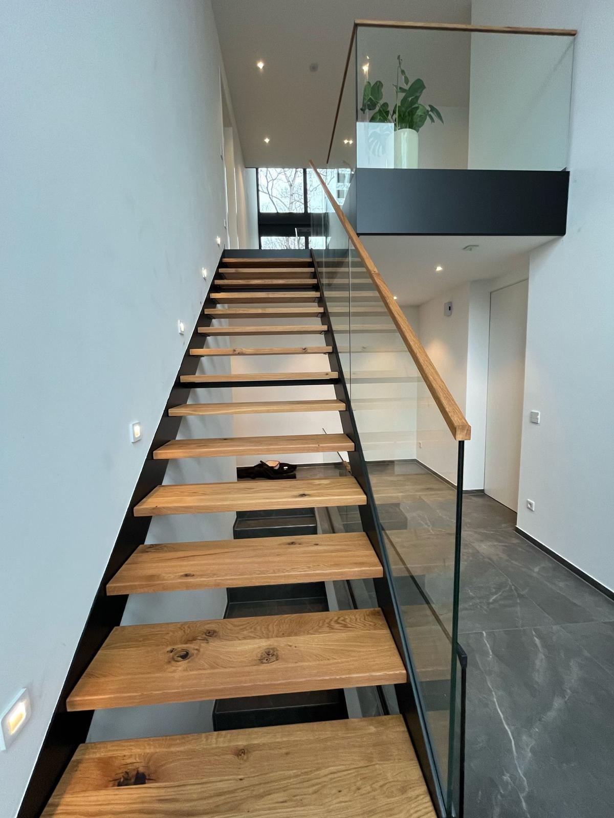 Stahltreppe innen mit Eichenstufen und Glasgeländer in modernem Wohnhaus